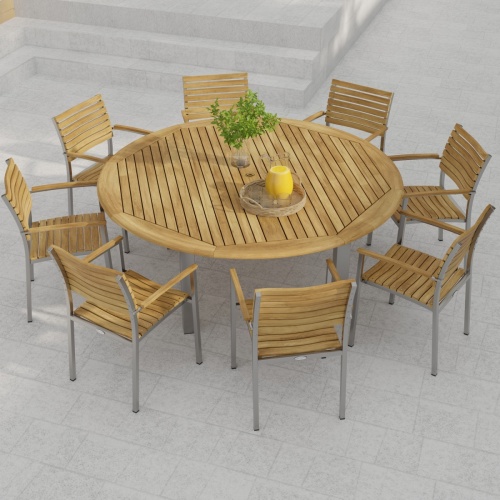 70111 Vogue teak and stainless steel 9 piece72 inch round Dining Set with a vase and a teak tray with a pitcher and 2 glasses in angled side view on stone patio with wall and plants in back
