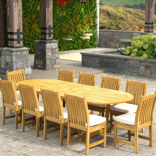 70166 Montserrat Veranda 11pc Dining Set with optional cushions on patio in angled end view with pergola with hanging plants and vines and landscape plants and hillside in background