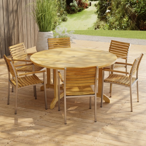 70349 Barbuda Vogue Teak 7 pc Dining Set in angled side view on paver patio with wood privacy wall with landscaping plants and trees in background