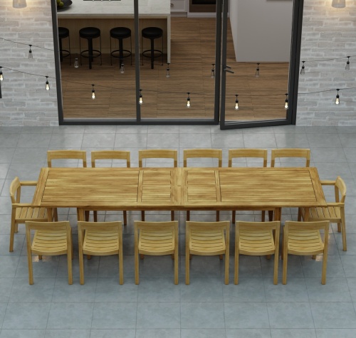 70353 Laguna 15 pc Teak Dining Set of 14 dining armchair and rectangular 11 foot extendable dining table angled aerial view in front of glass doors in the background 