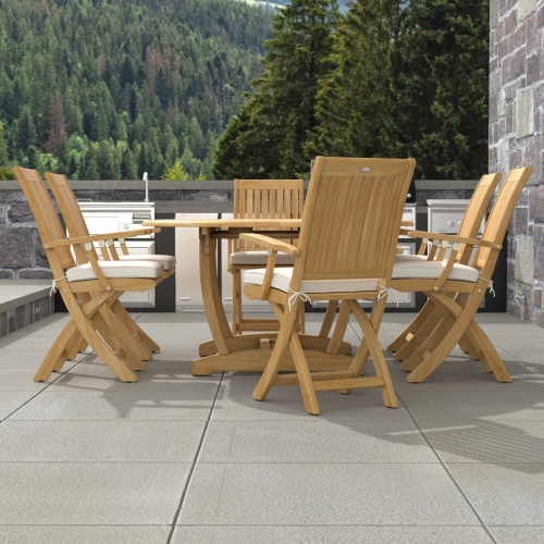 70368 Martinique Oval Barbuda Chair 7 pc Dining Set of Martinique Oval Table and 6 Barbuda Teak Arm Chairs with optional cushions in end view on patio with trees in the background