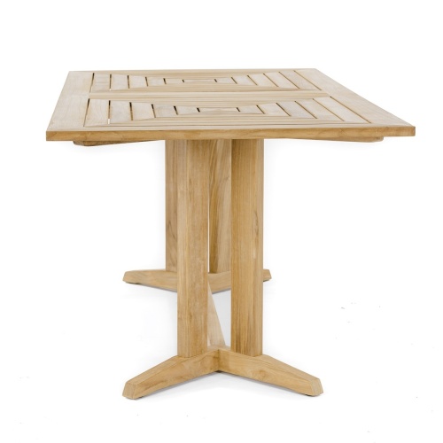 70435  Pyramid 14 pc Teak Dining Set on Teak Parquet floor deck angled aerial view in front of an outdoor fireplace with privacy wall and green lawn in background