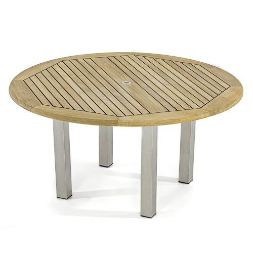 70439 Vogue Dining Set for 6 of Vogue Teak and Stainless Steel 60 inch Round Dining Table and 6 Vogue Side Dining Chairs angled aerial view with an outdoor fireplace in the background 