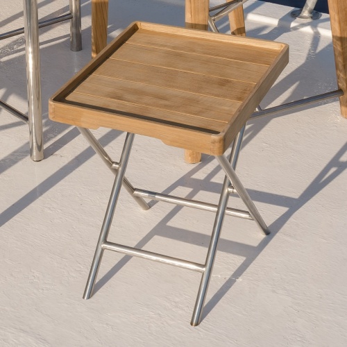 70460 Odyssey teak and stainless steel ottoman with teak serving tray aerial closeup view next to the Odyssey folding chair on boat deck