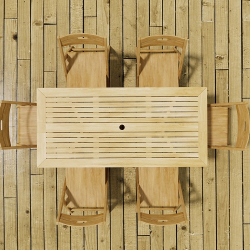 70472 Surf Nevis Teak 7 pc Dining Set with optional umbrella in angled aerial view on wood deck next to an outdoor fireplace with fence and hillside in background