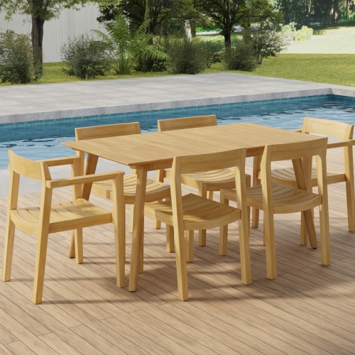 70525 Surf Horizon 7 pc Dining Set of a Surf Teak 60 inch Rectangular Table angled aerial view on patio in front of a pool with grass and landscaping plants and trees and white fence in the background