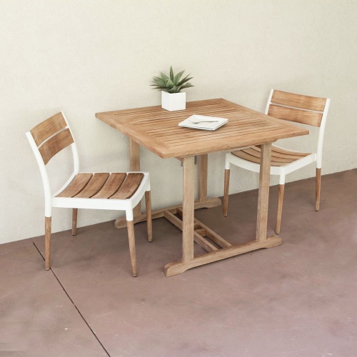 70653 Bloom teak and cast aluminum 3 piece Dinette Set showing a potted plant and 2 square plate with 2 forks on table top on covered patio against a wall 