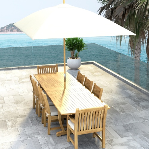 70792 Veranda 9 pc Teak Dining Set with optional seat cushions end view showing a potted plant and ocean view in background 
