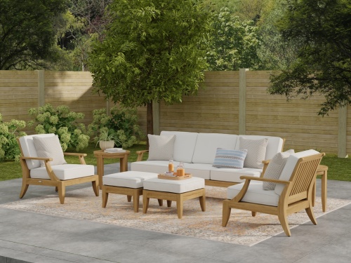 70871 Laguna 7 pc Conversation Set side view on a stone rock terrace with 3 potted plants and magazine and plates on ottoman with ocean in background 