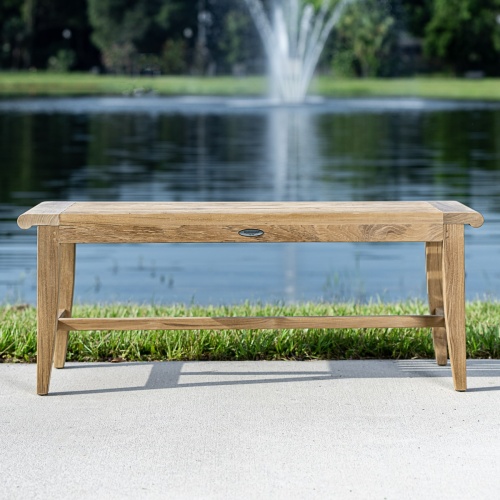 13915 Laguna 4 foot long teak Backless Bench on concrete walkway with grass and lake in background