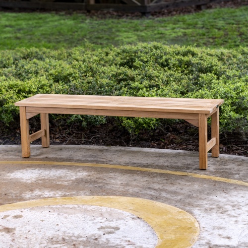 13929 Veranda teak 5 foot long Backless Bench side view on stone patio with bushes and concrete building in background
