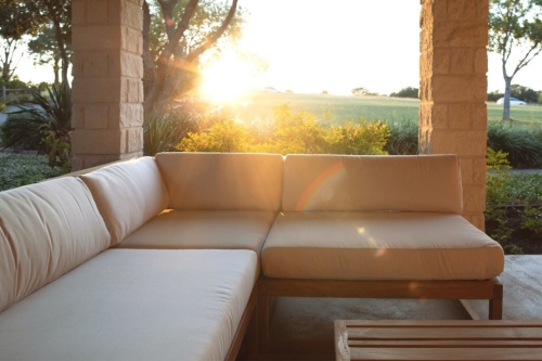 18800DP Maya Ottoman with Maya seating collection on outdoor patio with landscaped border and grassy field with trees background 