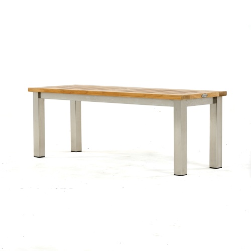  23940 Vogue teak and stainless steel 4 foot backless bench on concrete walkway with grass and house in background