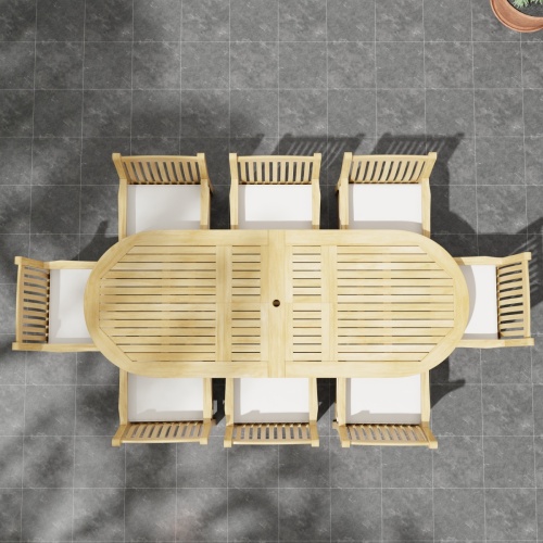 70178 Montserrat Veranda Teak 9 pc Dining Set of Montserrat Dining Table and 8 Veranda Side Chairs with optional seat cushions in end view on patio with planter of ferns and tree in the background