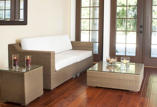 70241 malaga cushioned woven wicker sofa set interior location on wood floors with two lit pillar candles bowl mixed nuts floating candle on glass top tables with windows of outside view
