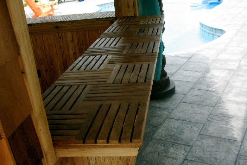 70401 parquet teak tiles closeup view of teak tiles on tiki bar counter on stone patio with pool in background
