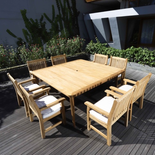 70878 Veranda 9 piece Square teak Dining Set angled view on wood deck with trees and bushes in background