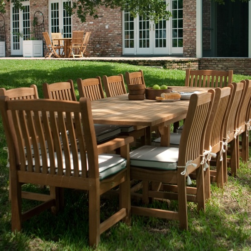 70017 Grand Veranda 13 piece dining set with optional seat cushions in aerial view showing bowl of apples plate of bread serving plates and bowls on a grass lawn