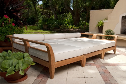 70100 Aman Dais 6 pc Daybed Set with cushions right side angled on stone patio three potted plants outdoor fireplace trees grass in background