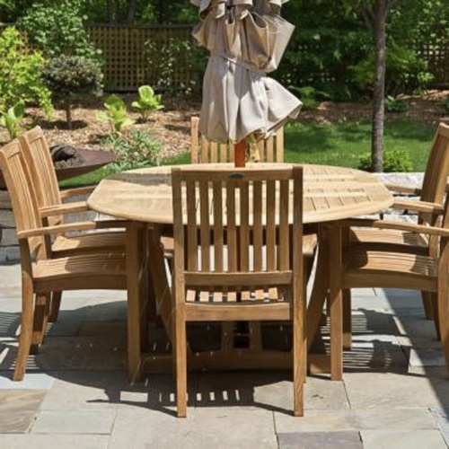 70214 Martinique Sussex Teak 7 pc Dining Set of Martinique Teak Oval Table and 6 Sussex Teak stacking Arm Chairs aerial view next to pool with plants in background