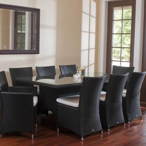 70262 Valencia Wicker 9 piece Dining Set with floating candle and 2 flower stems on table top and seat cushions on wood floors wall mirror in background and french doors to outside
