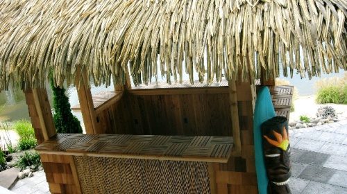 70401 parquet teak tiles on tiki bar counter on stone patio landscape plants and water in background