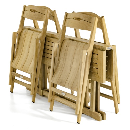 70472 Surf Nevis Teak 7 pc Dining Set of Nevis Dining Table and 6 Surf Folding Chairs in side view on wood deck in front of a fireplace and fence with the hillside in background