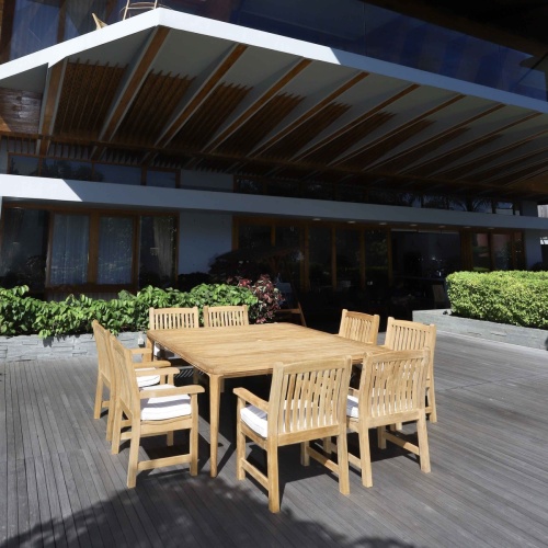 70878 Veranda 9 piece Square teak Dining Set with optional canvas colored seat cushions angled view on wood deck with flowers and house in background