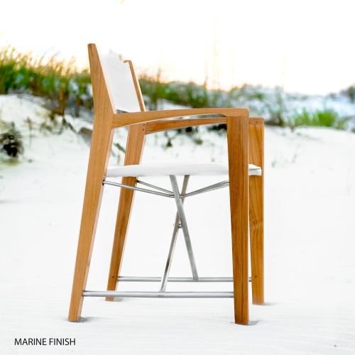 12915RF Refurbished Odyssey Director Chair in marine gloss finish right side view facing ocean on sandy beach with sand dunes and sea grass and blue sky in background