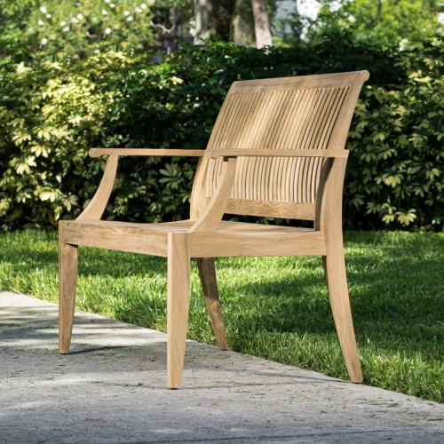 13810 Laguna 4 foot Teak Bench angled side view on concrete walkway with bushes and house in background