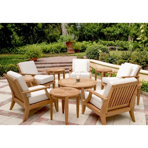 70106 Laguna 11 piece lounge set on stone patio with pillar candle and glass holder on coffee table brick stairs with potted plants landscape shrubs and trees in background