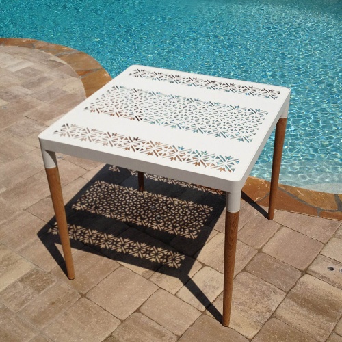 70489 Bloom teak and powder coated aluminum 32 inch square dining table on pool deck angled view of table with pool in background