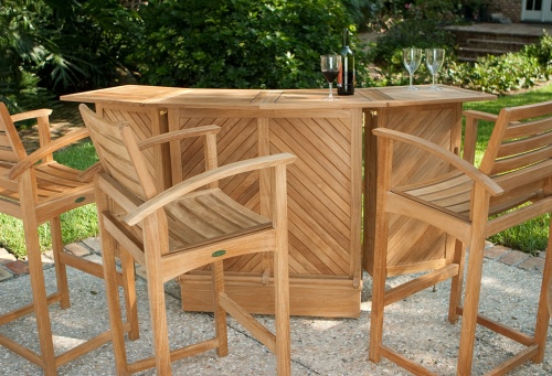 12466 Somerset 5 piece Teak High Bar Set with wine bottle and three wine glasses on concrete patio with trees in background