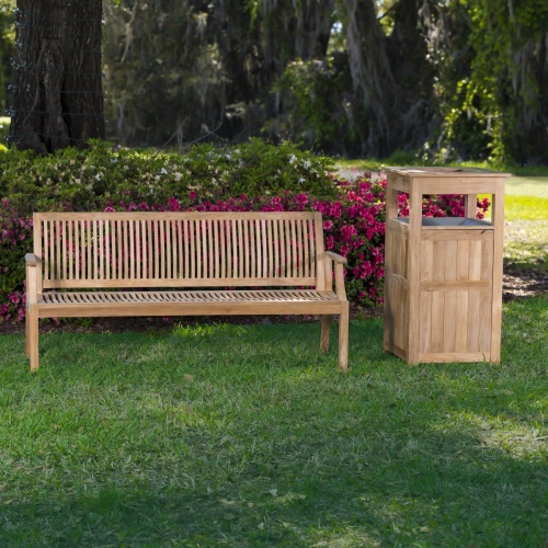 13812 Laguna 5 foot long Teak Bench beside teak teak Palazzo III trash receptacle on grass with flowering shrubs and trees in background