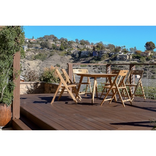 15917 Surf Teak Dining Table side view on deck overlooking houses on a hillside with natural vegetation in background