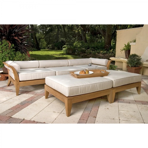 16767dp aman dais sectional set front view with bolsters and cushions a magazine and  teak tray with green apples on an outside patio with a grass landscaped background 
