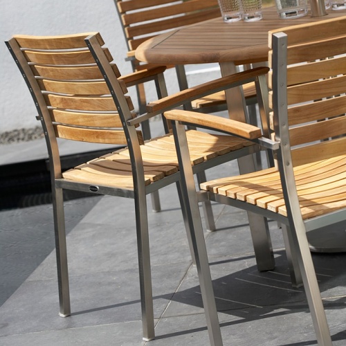 70111 Vogue teak and stainless steel 9 piece round dining set closeup partial view on concrete outdoor patio