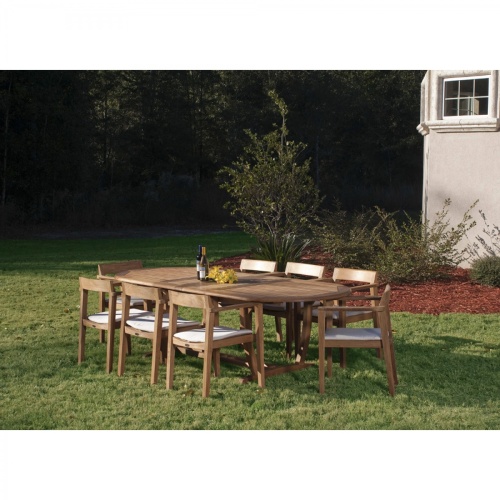 70255 Montserrat Horizon 9 piece Teak Dining Set with optional seat cushions on grass field with trees and shrubs in background