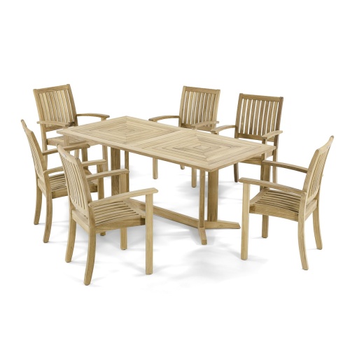 12196 Sussex teak stacking armchair with round teak dining table on stone patio with trees and shrubs in background