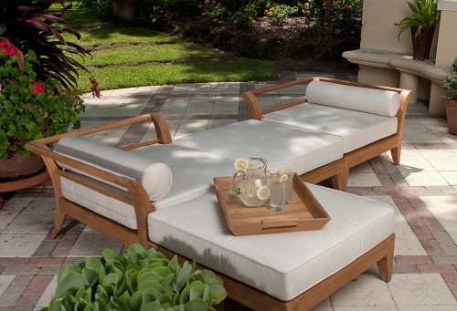 16765DP Aman Dais Corner Sectional set with bolsters and cushions angled on patio with a pitcher and two glasses of ice water and lemon slices on tray with three plant pots landscaped background