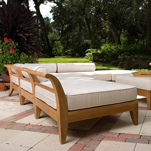  70121 Aman Dais 6 piece teak sectional set cushioned side angled showing back of end frame on a stone patio tray of green apples potted plants with grass lawn and trees in background