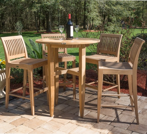 11910 Laguna 5pc Teak High Bar Set on Stone patio showing wine bottle and two wine glasses on table with trees and grass in background