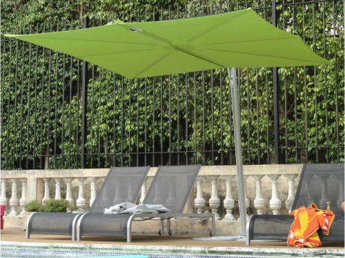 SP25100SET Spectra Solo Umbrella and Paver Base with three sling loungers with towels on two concrete railing black fence and landscaped trees in background
