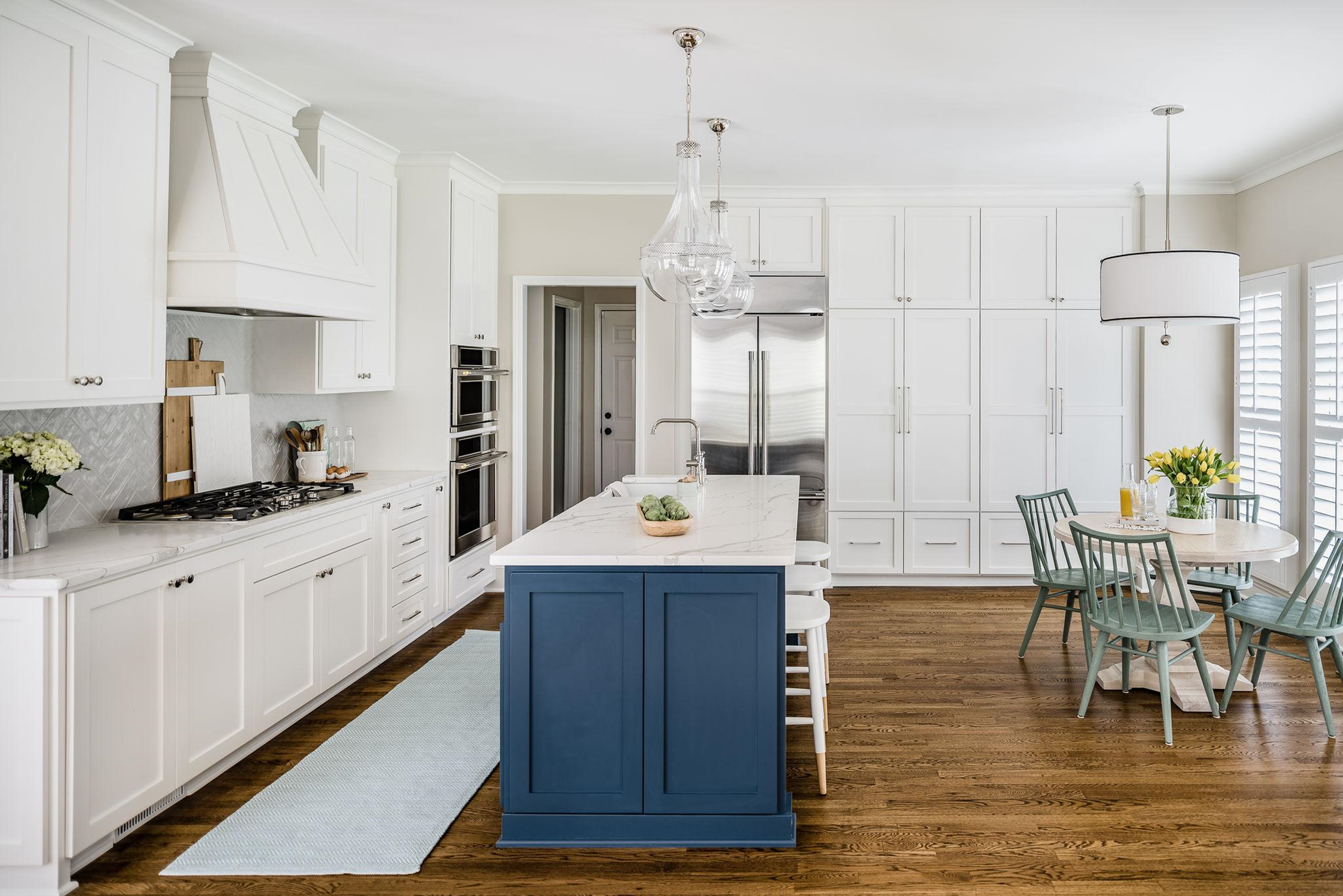 White kitchen with white marble counter tops and blue center island cabinet with 5 pc light green and white kitchen dining set