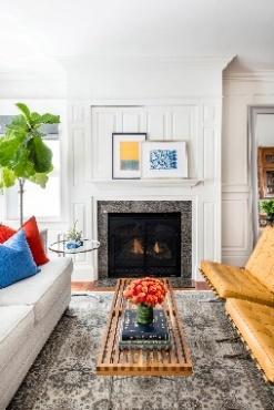 An image of 2 sofas facing each other with a fireplace and 2 hanging paintings above the mantle.