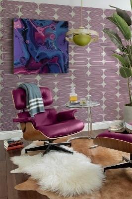 A Modern room showing a leather and wood chair on a fur rug and a modern painting in the background.