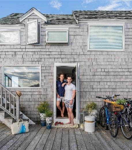 An Image Trevor Fulmer and Jim at the doorway of their seaside condo with a bike and potted plants next to the doorway.
